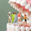 Miniature di sportivi che corrono sopra una fila di denti