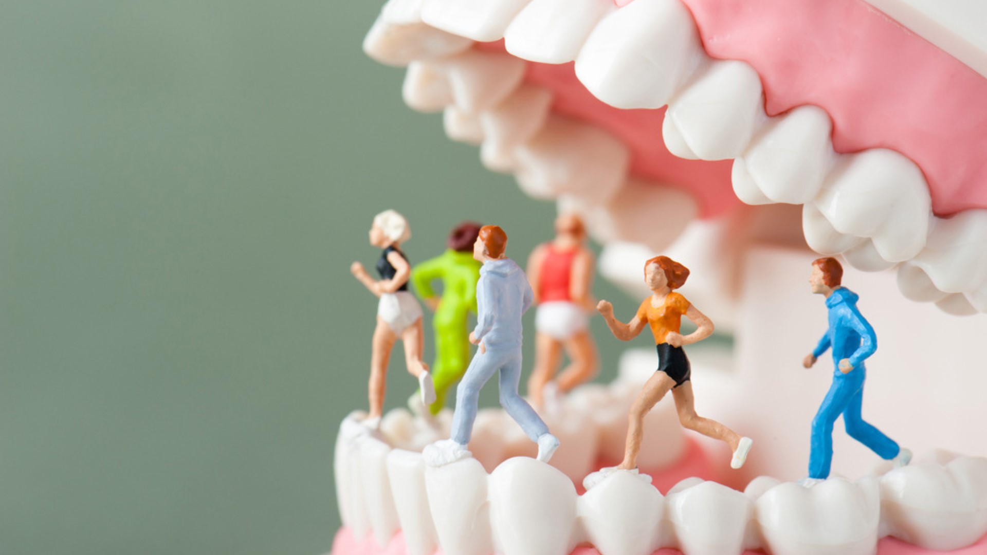Miniature di sportivi che corrono sopra una fila di denti