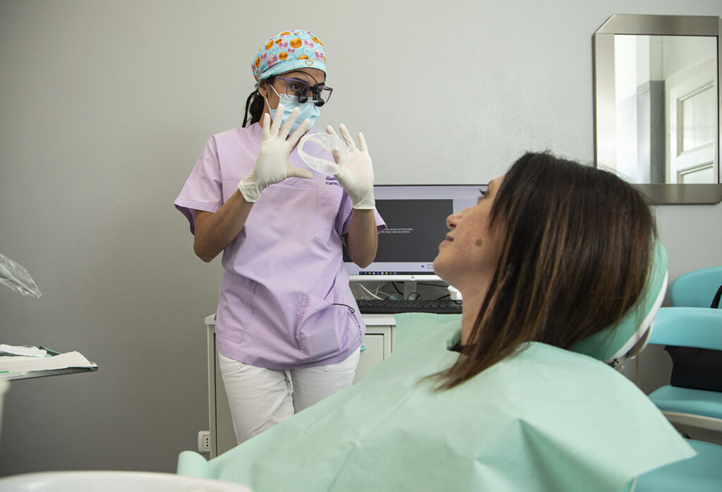 Professionista dello Studio Ferman che mostra alla paziente le mascherine su misura per il trattamento di sbiancamento dentale